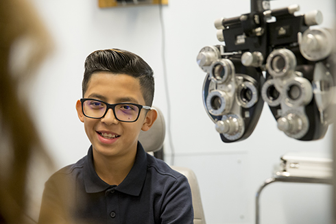 Teen boy with glasses has his eyes examined at Casey Eye Institute