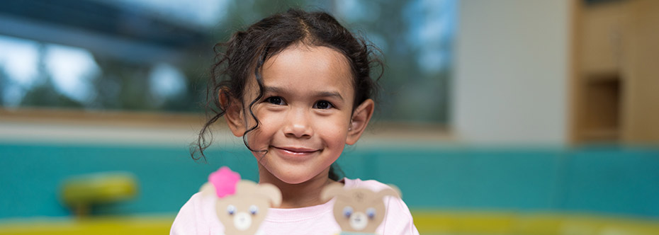 Photo of a girl smiling and holding paper teddy bears.