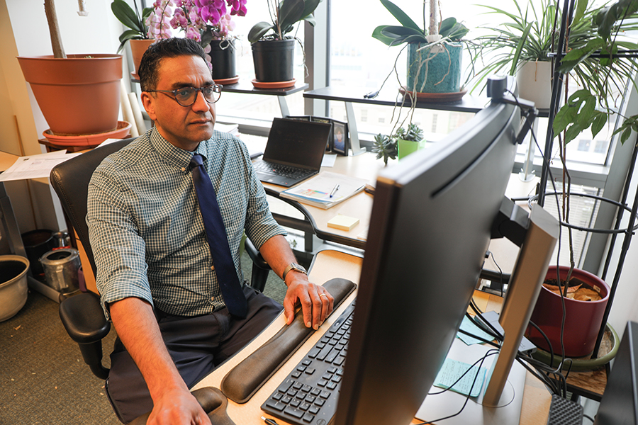 A doctor seen working at his desk on his computer.