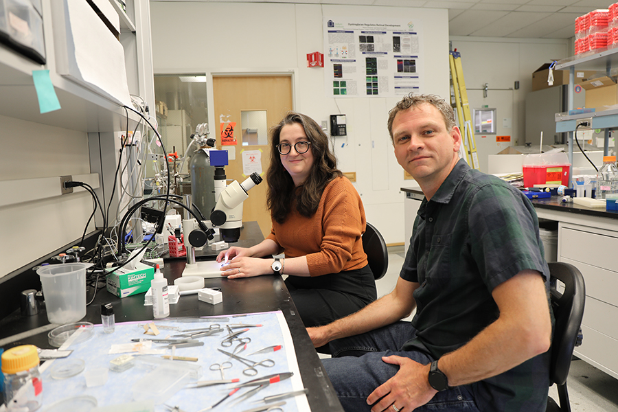 A man and a woman seated at a counter in a research lab.