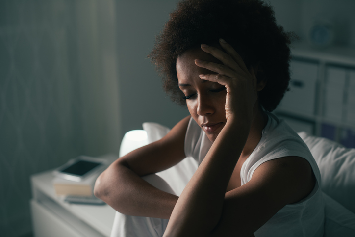 woman in dark room holds head