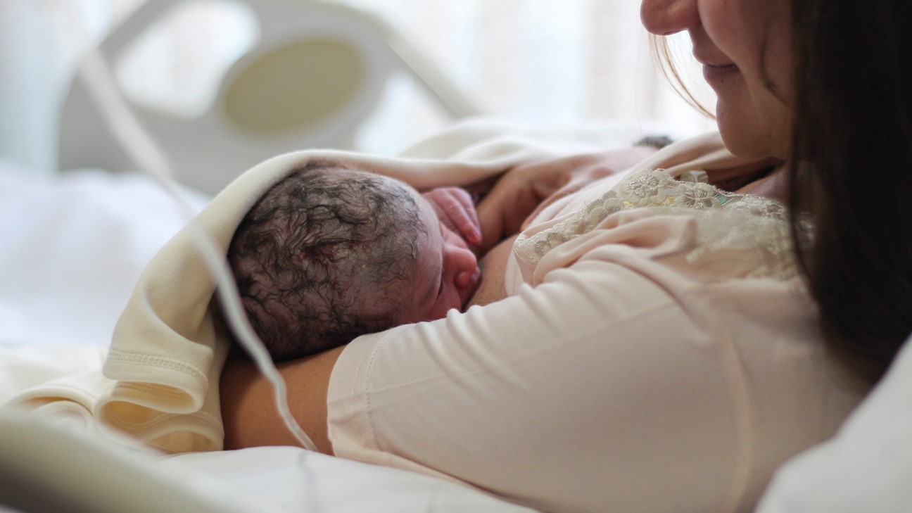 A parent breastfeeds a baby after birth in hospital