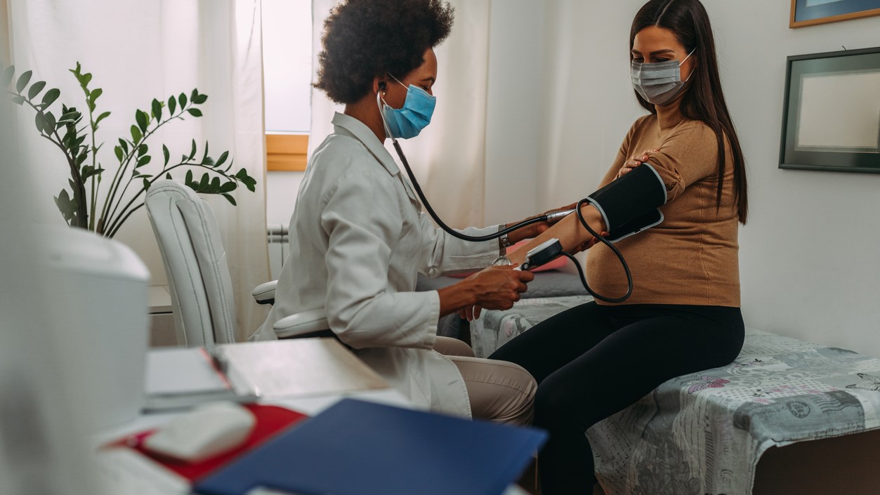 A provider takes a pregnant patient's blood pressure in the clinic.