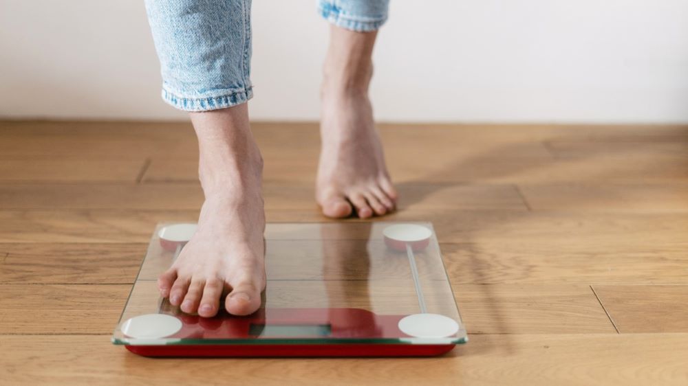 A close shot of a person stepping on a glass scale in bare feet.