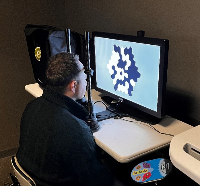 Man sits in front of a monitor taking a vision test.