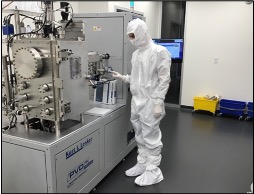 An OHSU researcher wearing their Nanofab suit is standing in the CEDAR Nanofabrication Facility. 