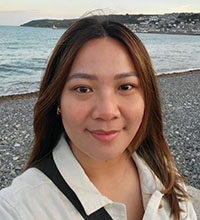 A headshot of Savy Louie with the ocean and beach behind her.