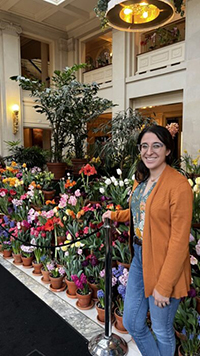 Carley Haft standing in front of a group of colorful flowers in terracotta pots.
