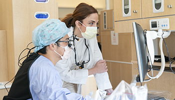 Two dental students work on a computer in a lab.