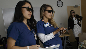 Two radiation therapy students practice skills during a simulation.