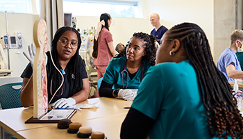 Three nursing students learn in the simulation lab.