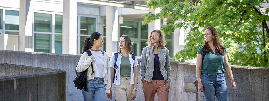 Four students walk outside on the OHSU campus on a sunny day.