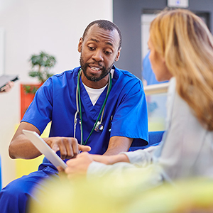 A doctor sits with a student patient and reviews paperwork.