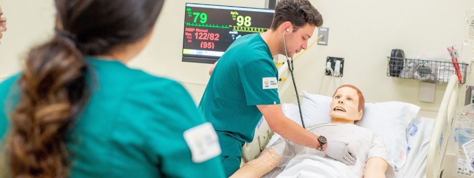 Two students in green scrubs working on a Manekin in the OHSU simulation lab.