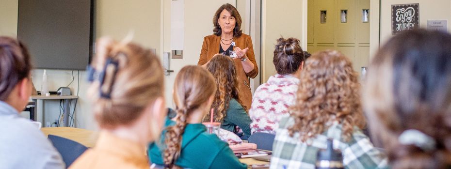 A nursing faculty member teaches to students in a classroom setting.