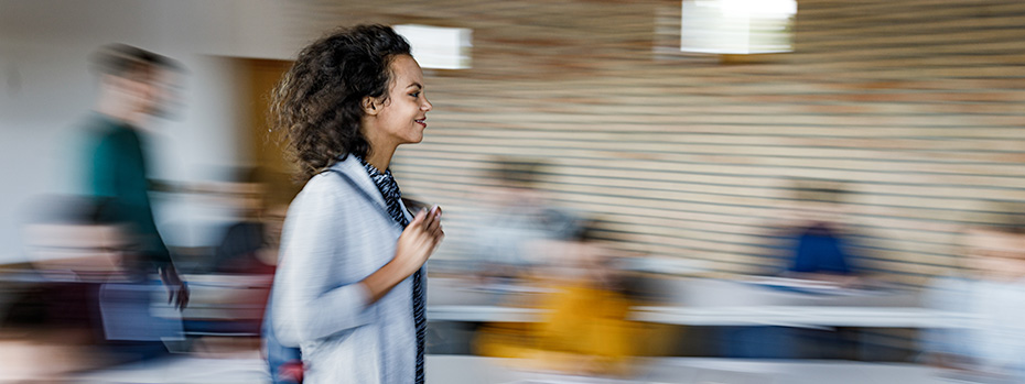 A student smiles while walking across the front of a classroom.