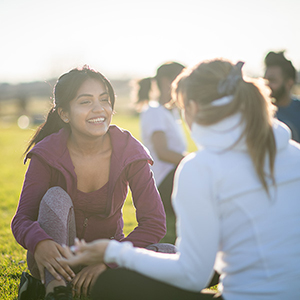  Students sit outside on the grass on a sunny, clear day.