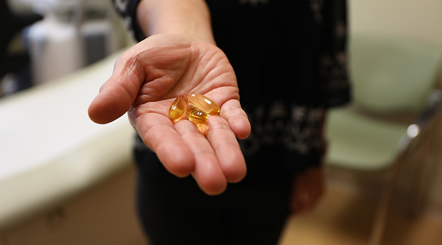 A hand holding fish oil supplement pills.