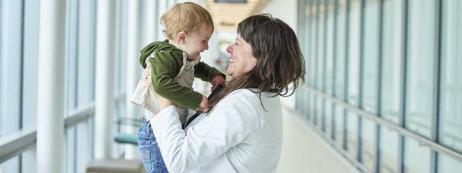 OHSU surgeon Lori K. Howell holds a toddler and shares a smile with him.