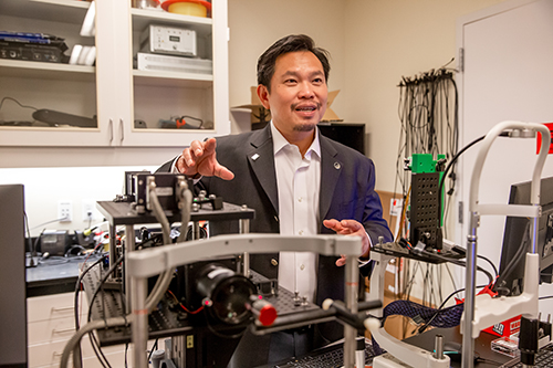 Dr. David Huang stands next to equipment in Oregon Health & Science University’s Center for Ophthalmic Optics and Lasers.