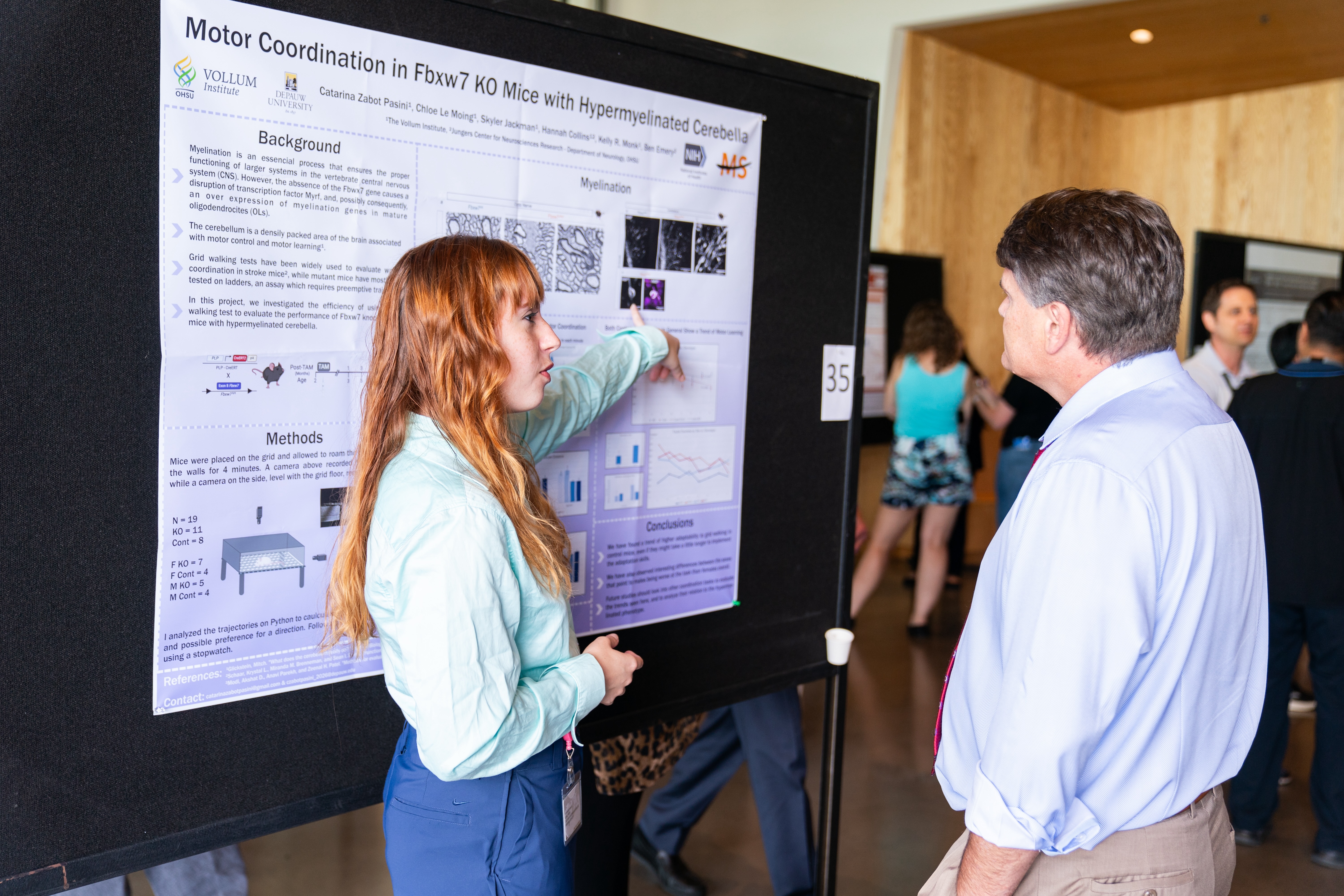 Intern presents poster to onlooker.