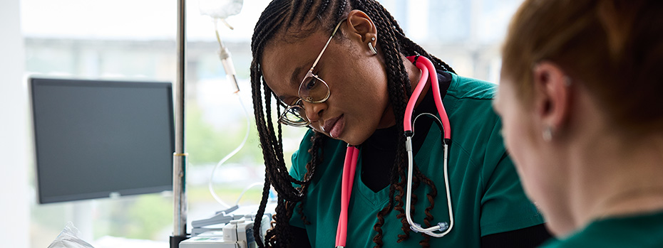 Two OHSU nursing students wearing scrubs review patient information.