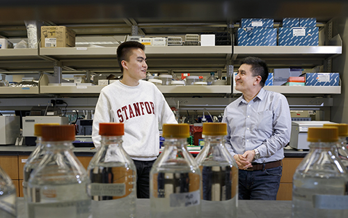 Dr. Mitalipov and his son, Paul, stand chatting in a laboratory at OHSU.