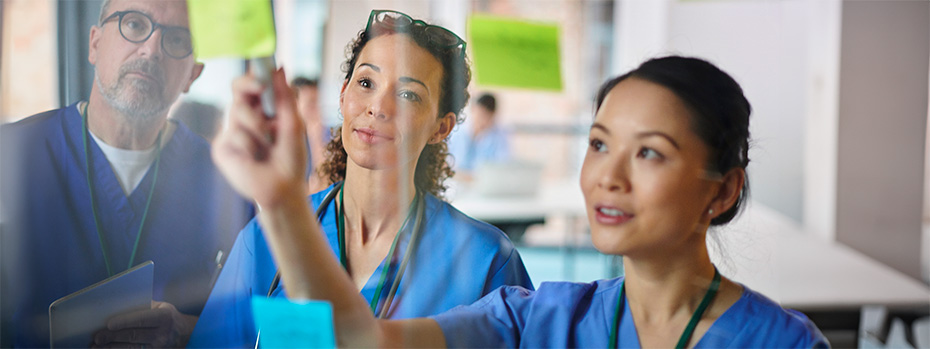 Three OHSU nursing students wearing scrubs review patient information.