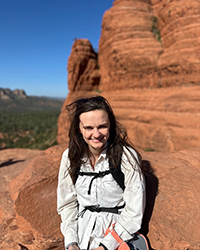 A woman smiling while hiking up a mountain on a warm sunny day.