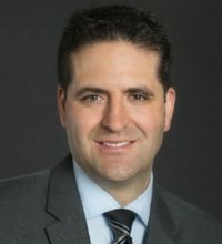 Headshot of man, smiling in a gray suit