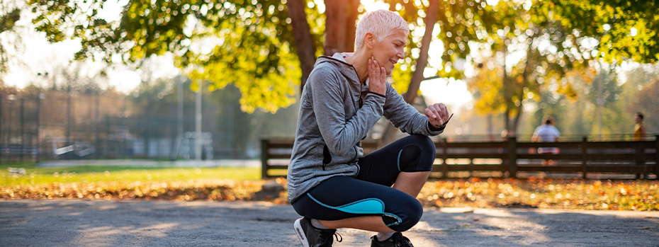 A woman checks her heart rate after going for a jog in a park.