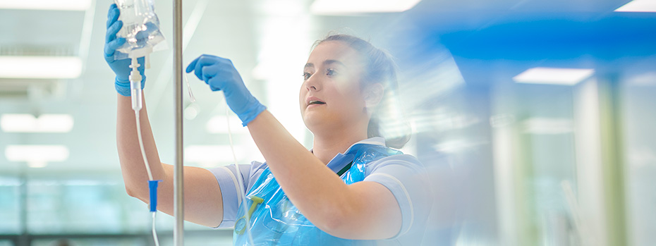 An OHSU School of Nursing student prepares an IV bag in a clinical lab.