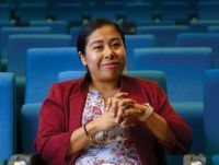 Professional portrait of Dr. Vasquez Guzman sitting in a auditorium with blue chairs.