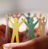 A close-up of a person holding little paper cutouts of people