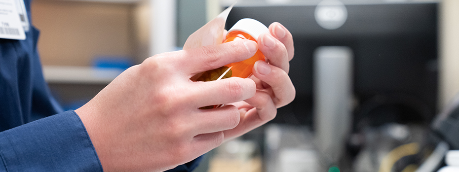 An OHSU Pharmacy employee puts a label on a pill bottle.