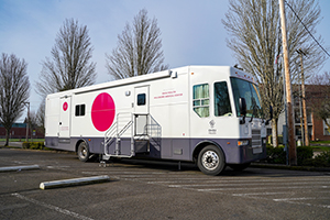 A white RV-style van parked in a parking lot with text on the side that reads "OHSU Health Hillsboro Medical Center."