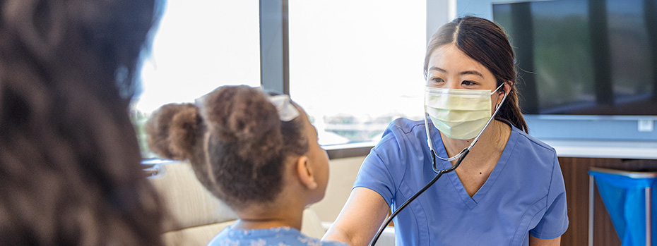 OHSU nursing student wearing a stethoscope, listening to a child’s heartbeat during a clinical practice session.