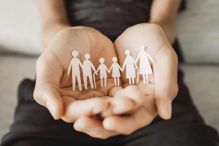 hands holding a cutout of a family.