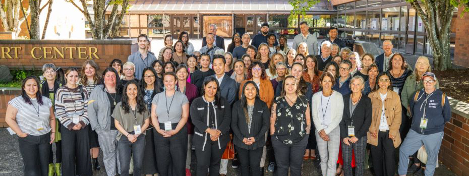 Image of approximately 80 attendees of the 2024 grantee conference standing on steps outside the conference center.