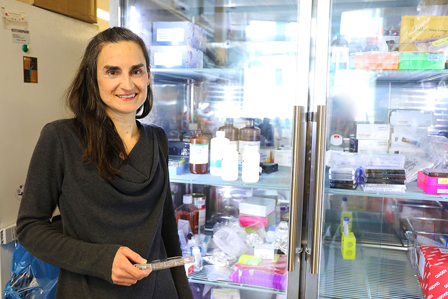 Laura Heiser, Ph.D., has short dark hair, black top, and is smiling at Knight Cancer Institute.
