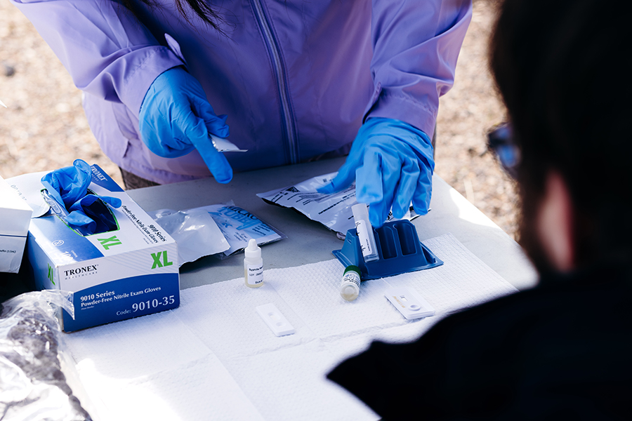 Peer counselor wearing gloves hand medication at an outreach event.